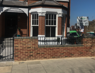 Black metal railings and matching pedestrian gate installed at a residential property in London.