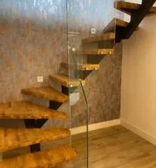 Bespoke floating wooden staircase with central steel spine and structural glass balustrade fabricated by Has Metal Work.